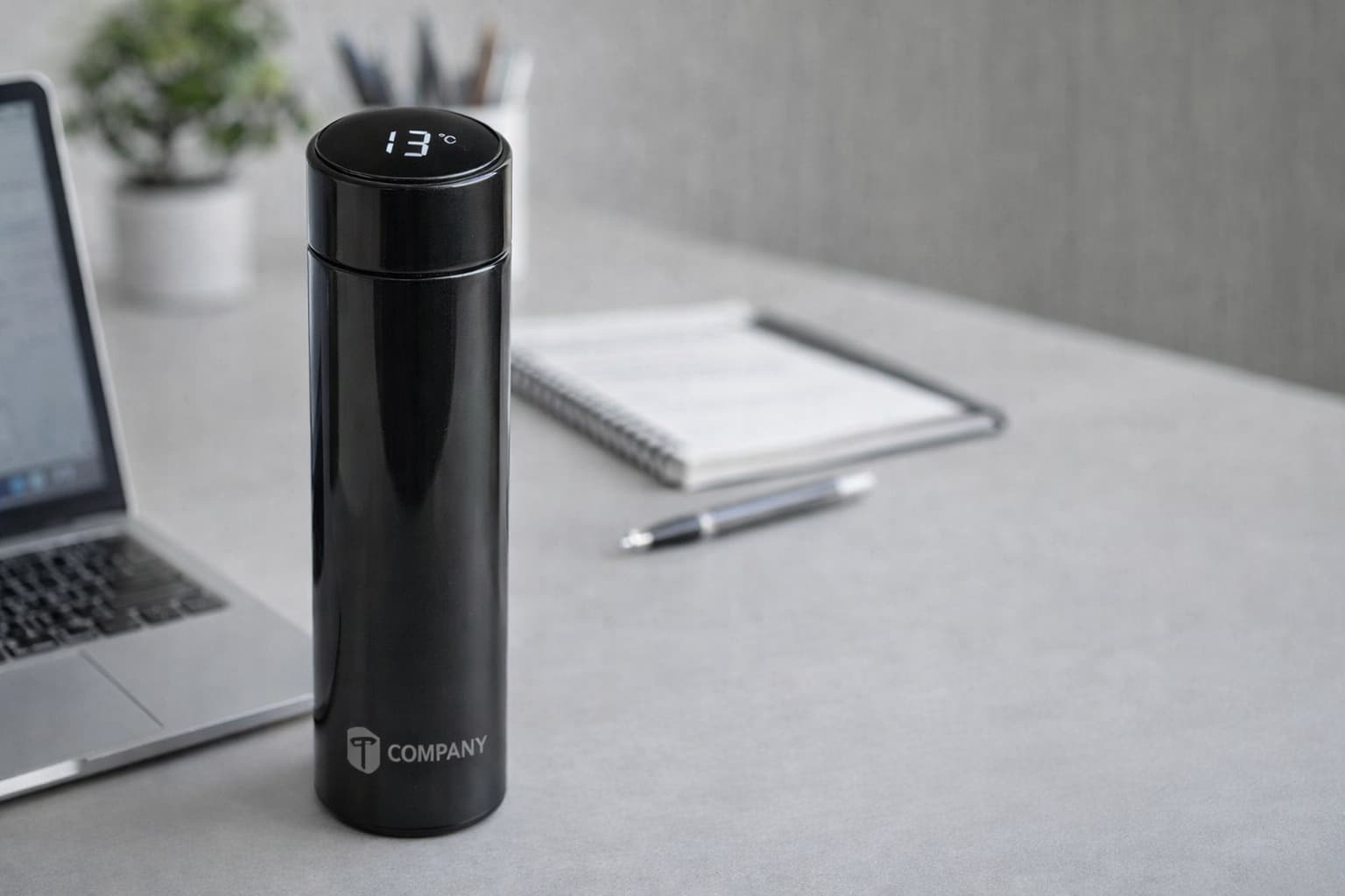 Black smart temperature display tumbler with laser engraved company logo on an office desk