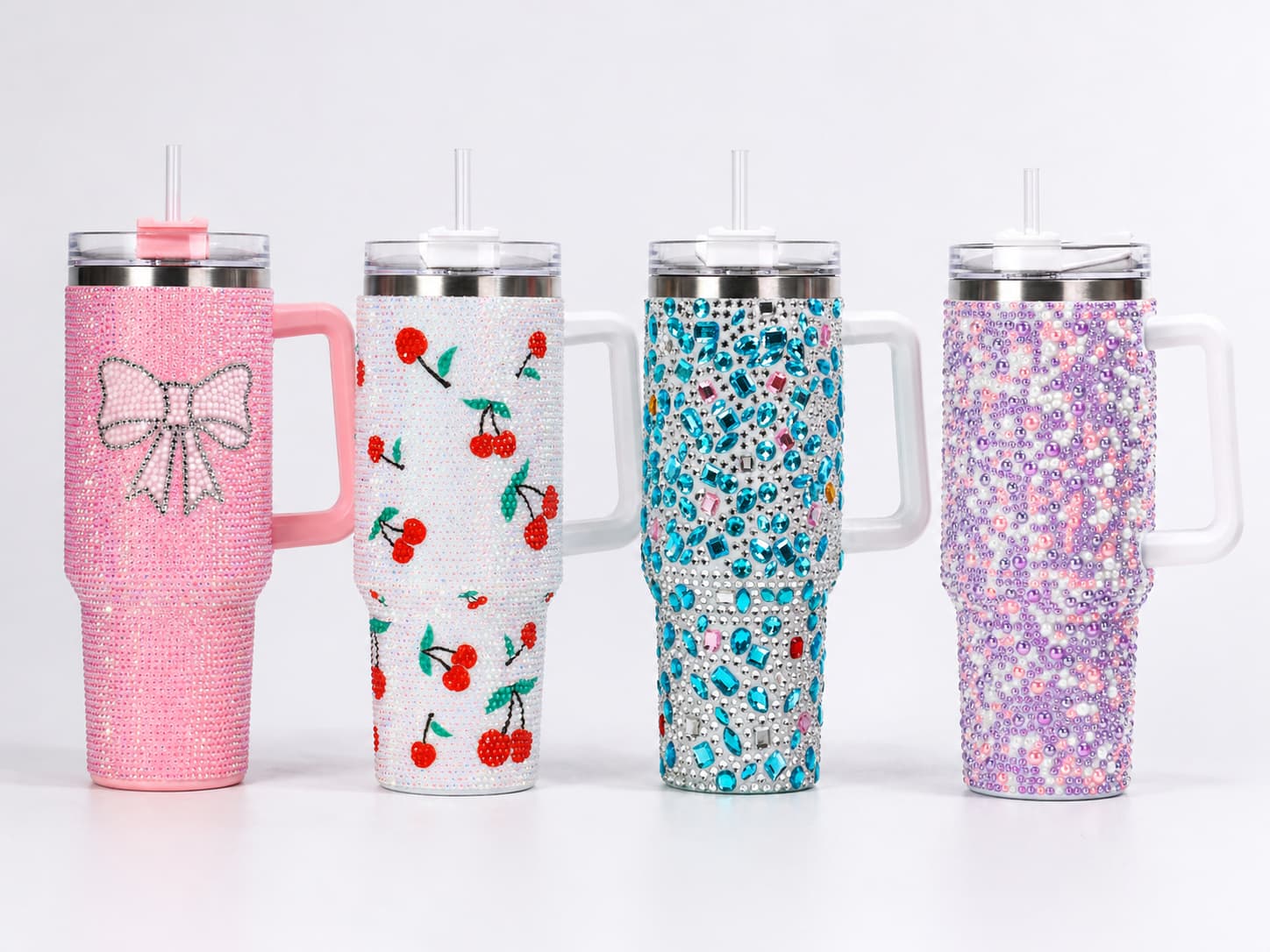 Four rhinestone tumblers with different finish styles, including resin rhinestone, acrylic gem, pearl finish, and decorative mixed-color layout, displayed on a clean studio background