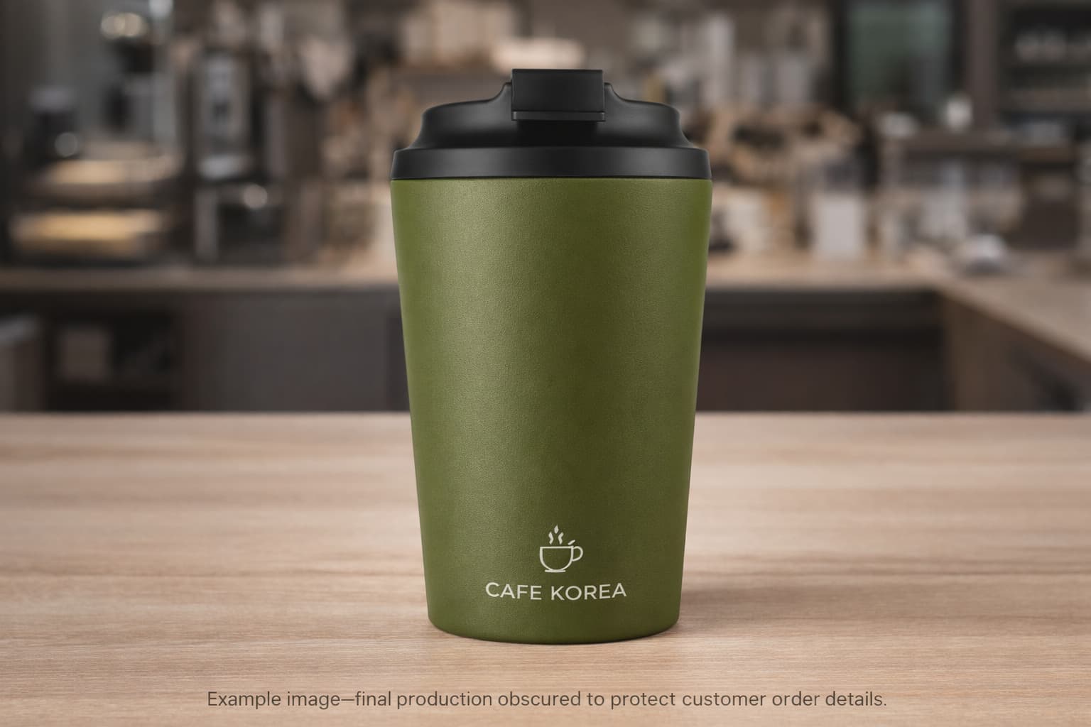 Olive green matte insulated tumbler with laser-style cafe logo in a coffee shop setting, concept image for custom member gift project.