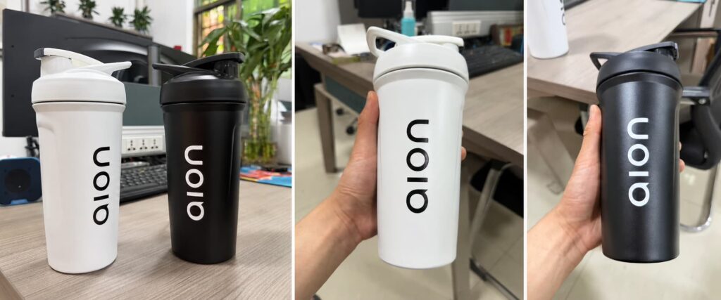 Custom 24oz 316 stainless steel protein shaker cups in black and white with single-color 3D logos, shown as sample cups for a U.S. fitness brand gift project.