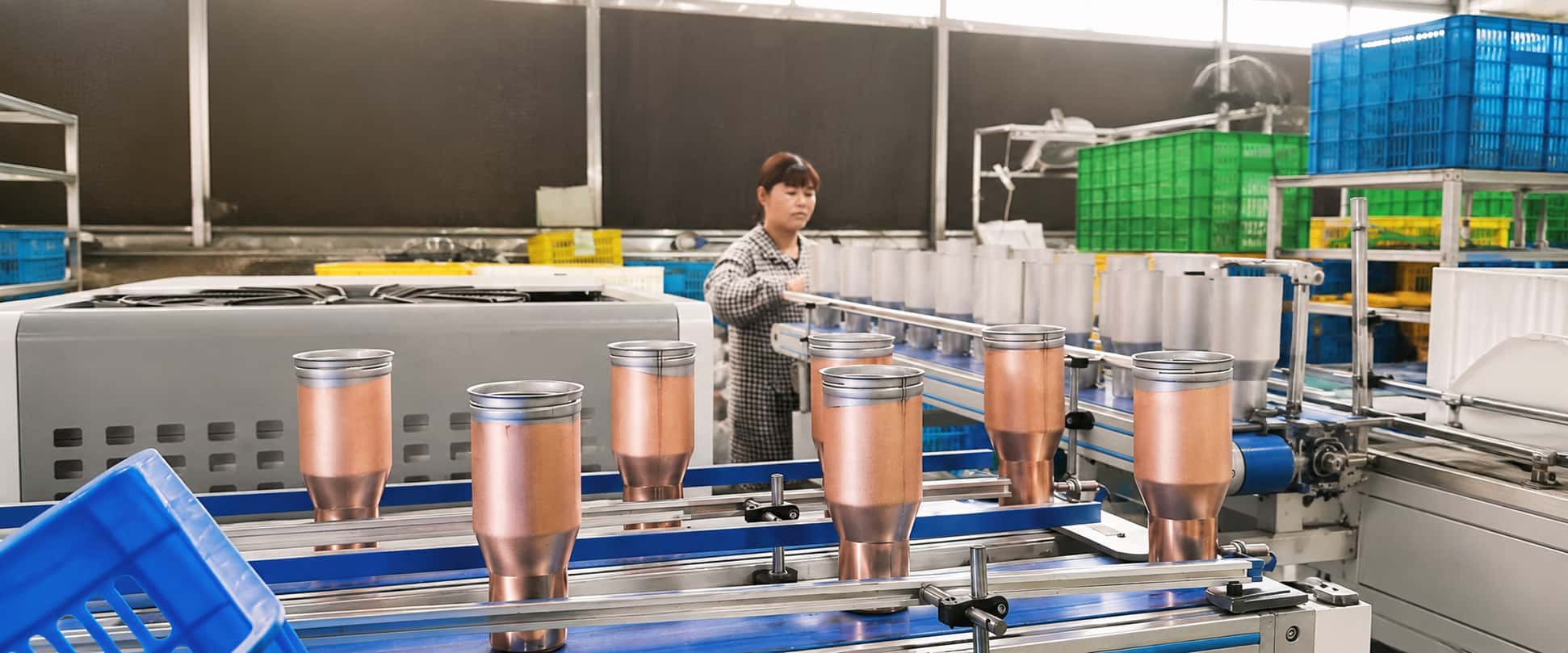 Stainless steel insulated bottle production line with semi-finished tumblers and a factory worker